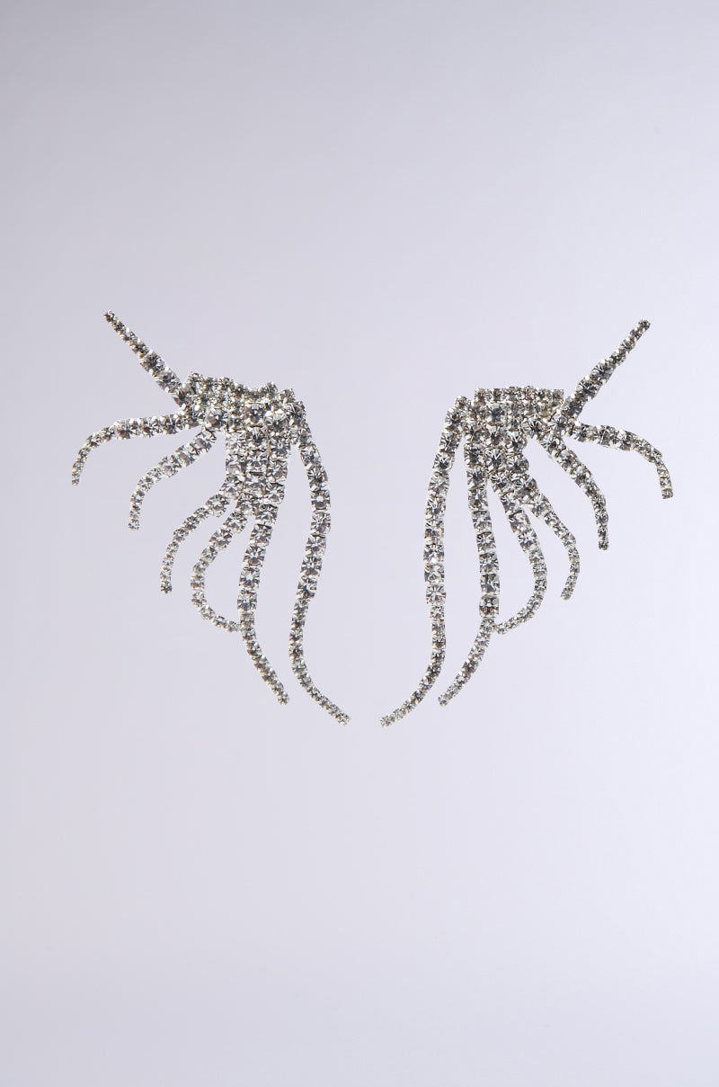 The IN MY ZONE SILVER EARRING features two sparkling, silver crystal earrings shaped like abstract wings or tentacles against a light gray background, with delicate rhinestone strands for added elegance. 2