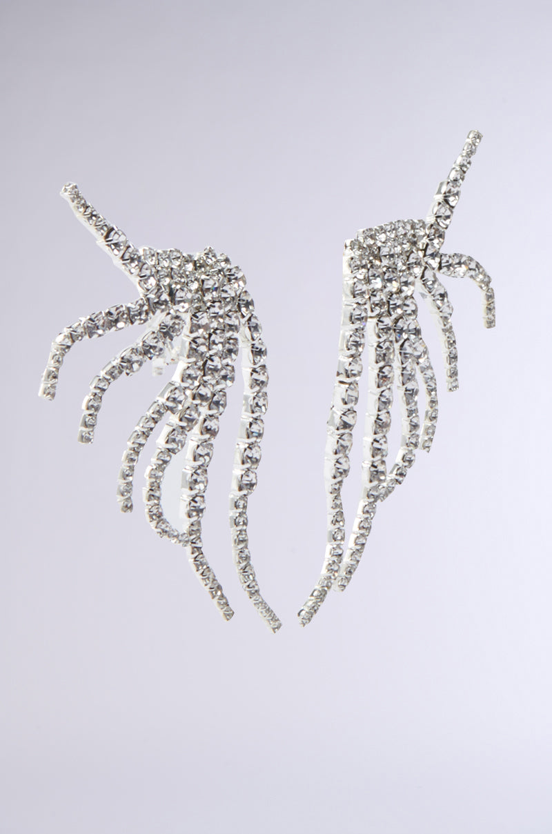 The IN MY ZONE SILVER EARRING features sparkling ear cuffs with curved, dangling rhinestone strands resembling abstract wings or feathers, shown against a plain light gray background. 3