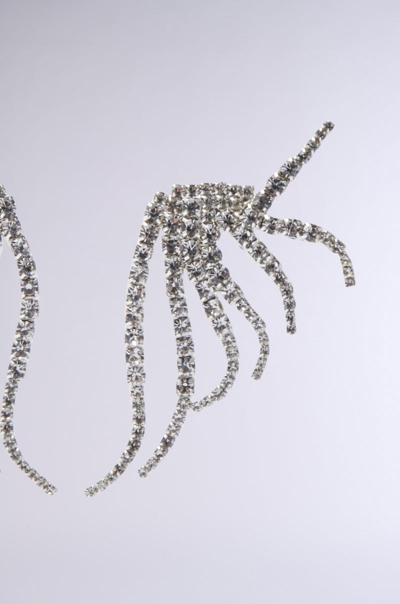 Close-up of sparkling rhinestone strands arranged in an abstract, fan-like shape on a plain gray background, resembling the elegant IN MY ZONE SILVER EARRING. 4