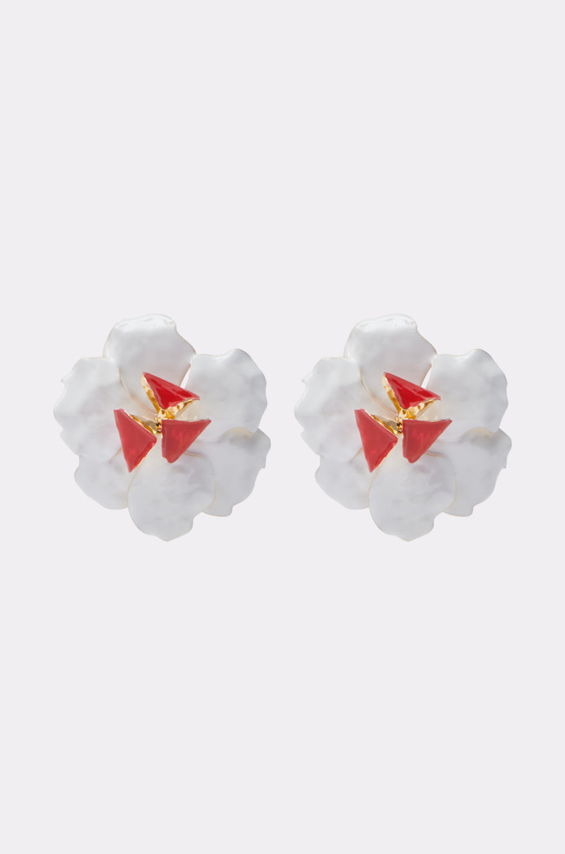 The FLORAL GARDEN EARRING features oversized white flowers with sculptural petals, gold centers, and three red triangular accents on each motif, shown against a plain light background. 1