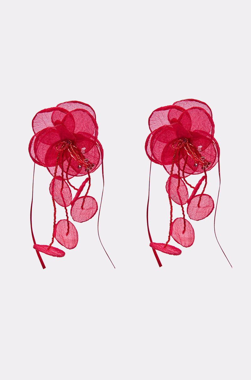The SIPPIN WINE EARRING features two vibrant red organza flowers with layered petals, ribbons, and delicate circular accents, creating an enchanting bloom silhouette against a plain light background. 1