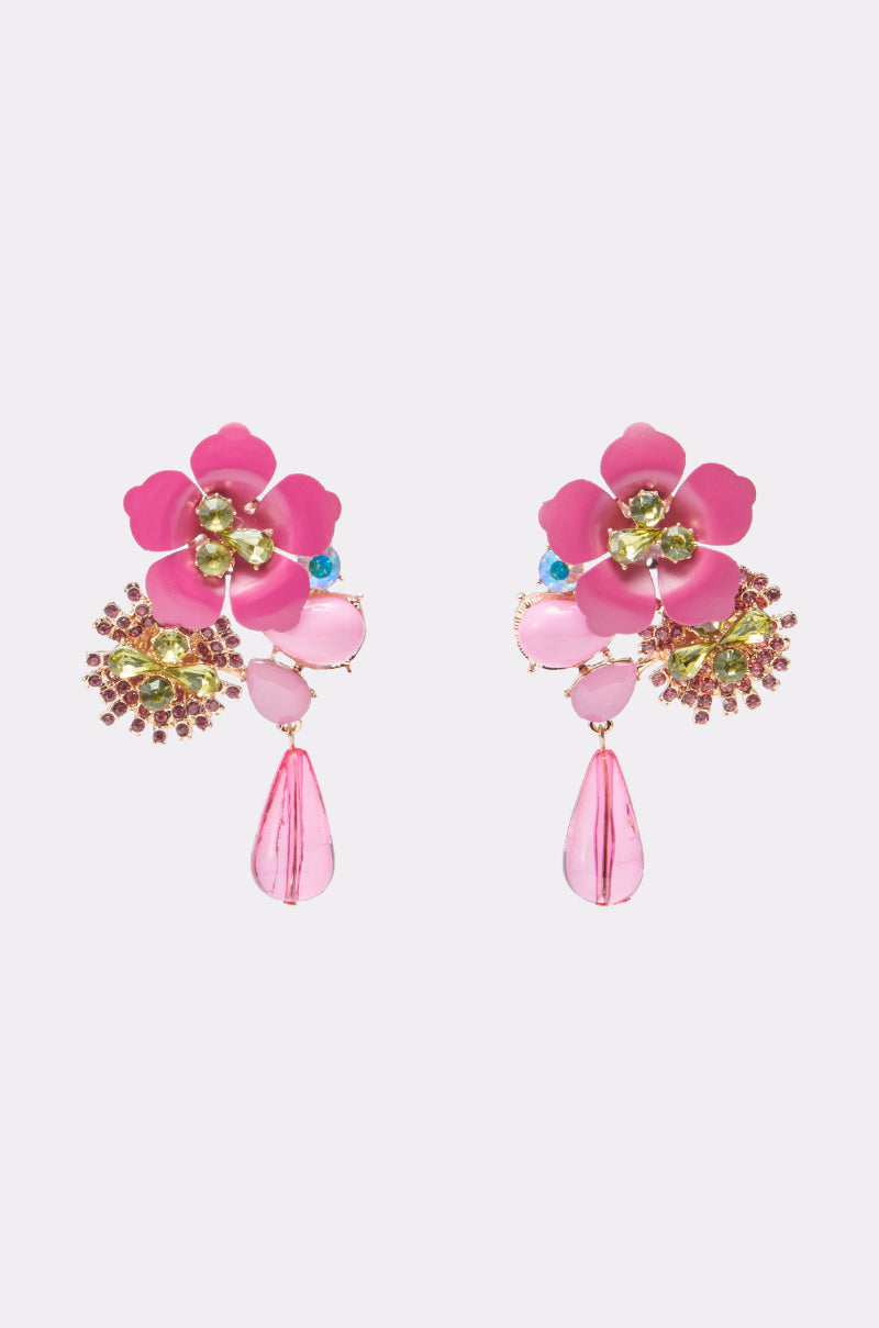 The BLISS EARRING is a vibrant statement piece with pink flower tops, crystal centers, yellow and blue accents, and pink teardrop dangles set against a light background. 0