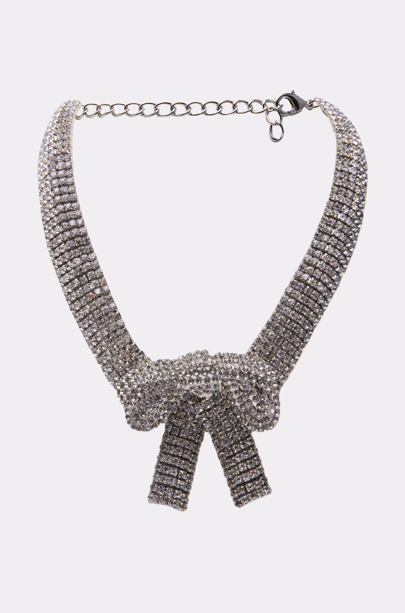 The GABBY BOW NECKLACE features a sparkling rhinestone bow centerpiece and an adjustable chain clasp, creating a stunning statement piece. 0