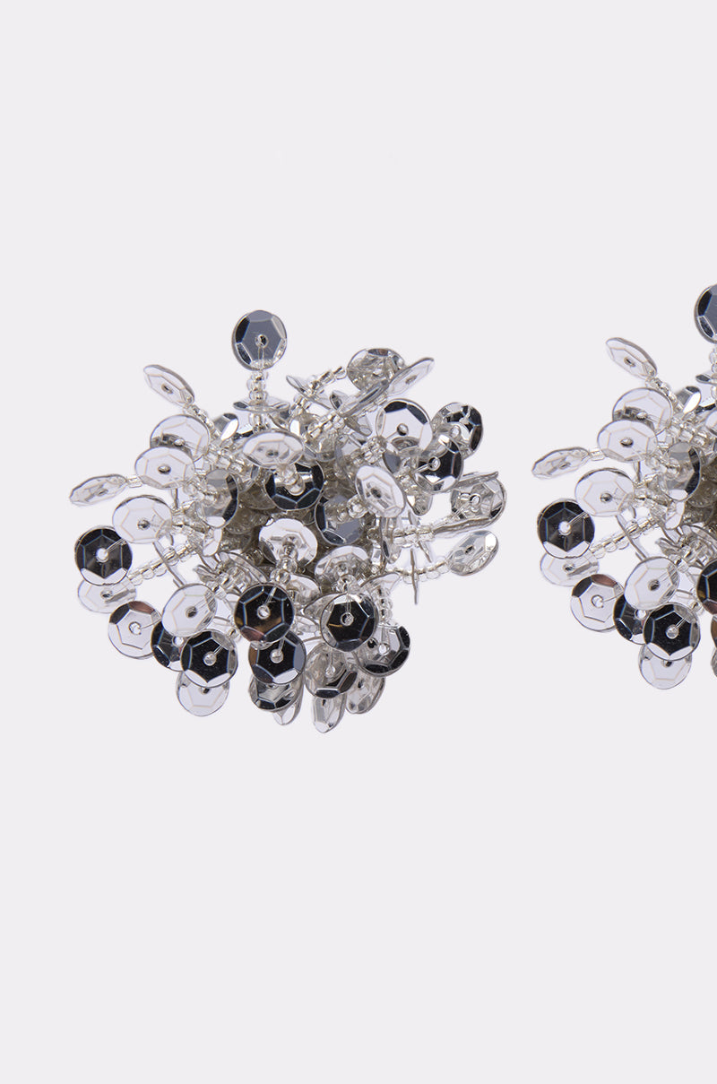 Two intricate STELLAR EARRING pieces feature clustered metallic and black sequins in a floral, spherical design with silver-tone accents. Both earrings are partially visible against a white background. 3