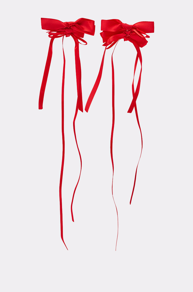 The LACED UP EARRING features two bright red satin ribbon bows with long, trailing ends, displayed on a plain light gray background. 2