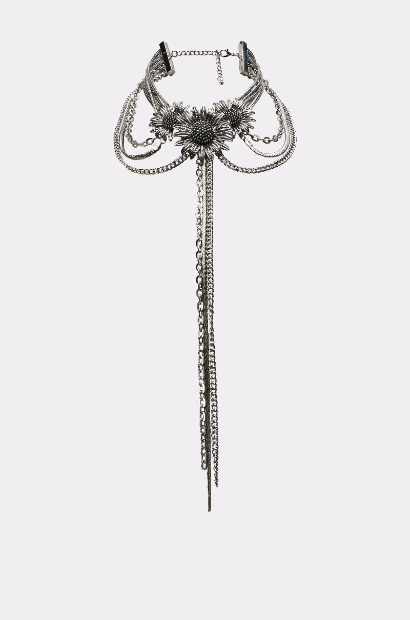 The NOT KANSAS ANYMORE NECKLACE is a silver layered choker with a bold central floral motif and long, dangling chain strands. 2