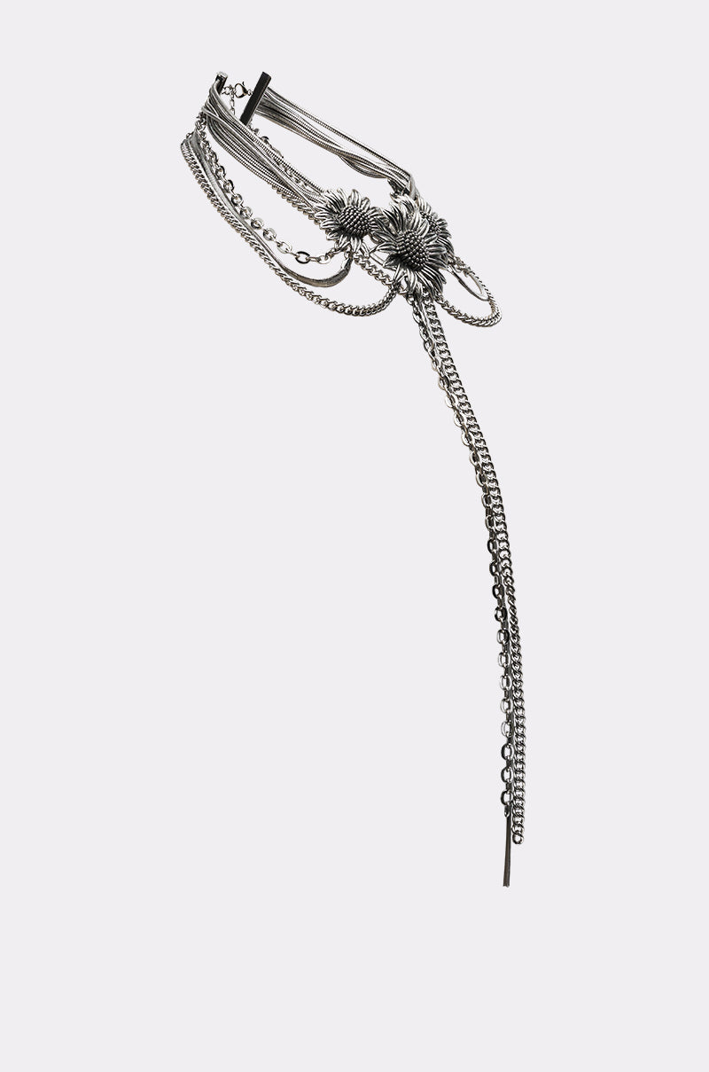 The NOT KANSAS ANYMORE NECKLACE is a silver-toned, multi-layered chain necklace with detailed floral metalwork and a long, dangling extension, shown on a plain light background. 3