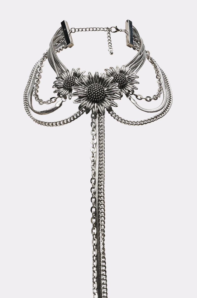 The NOT KANSAS ANYMORE NECKLACE is a silver statement piece with three large sunflower designs at the center, layered chains, and long cascading chain accents, displayed on a white background. 4