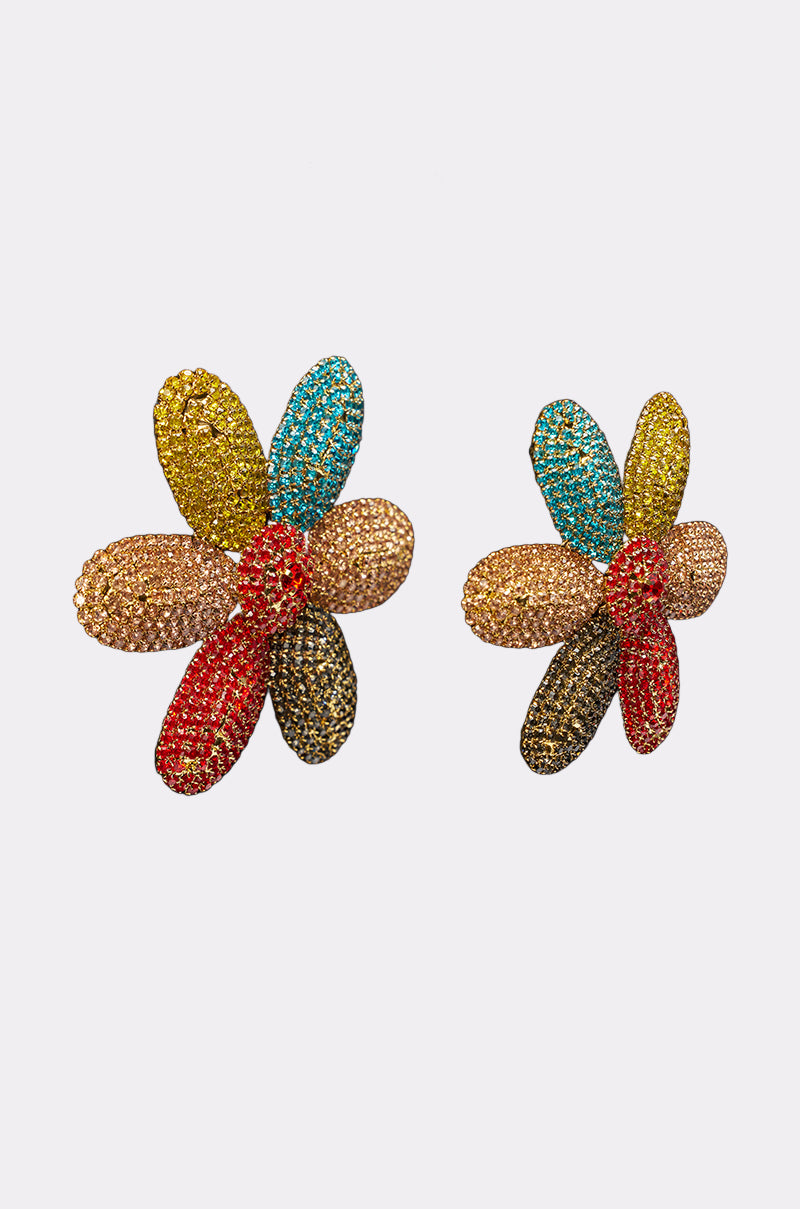 The TAKE ME TO JAPAN EARRING features five oversized, petal-shaped segments adorned with colorful crystals—red, yellow, blue, gold, and brown—creating bold floral statement earrings that stand out against a plain white background. 2