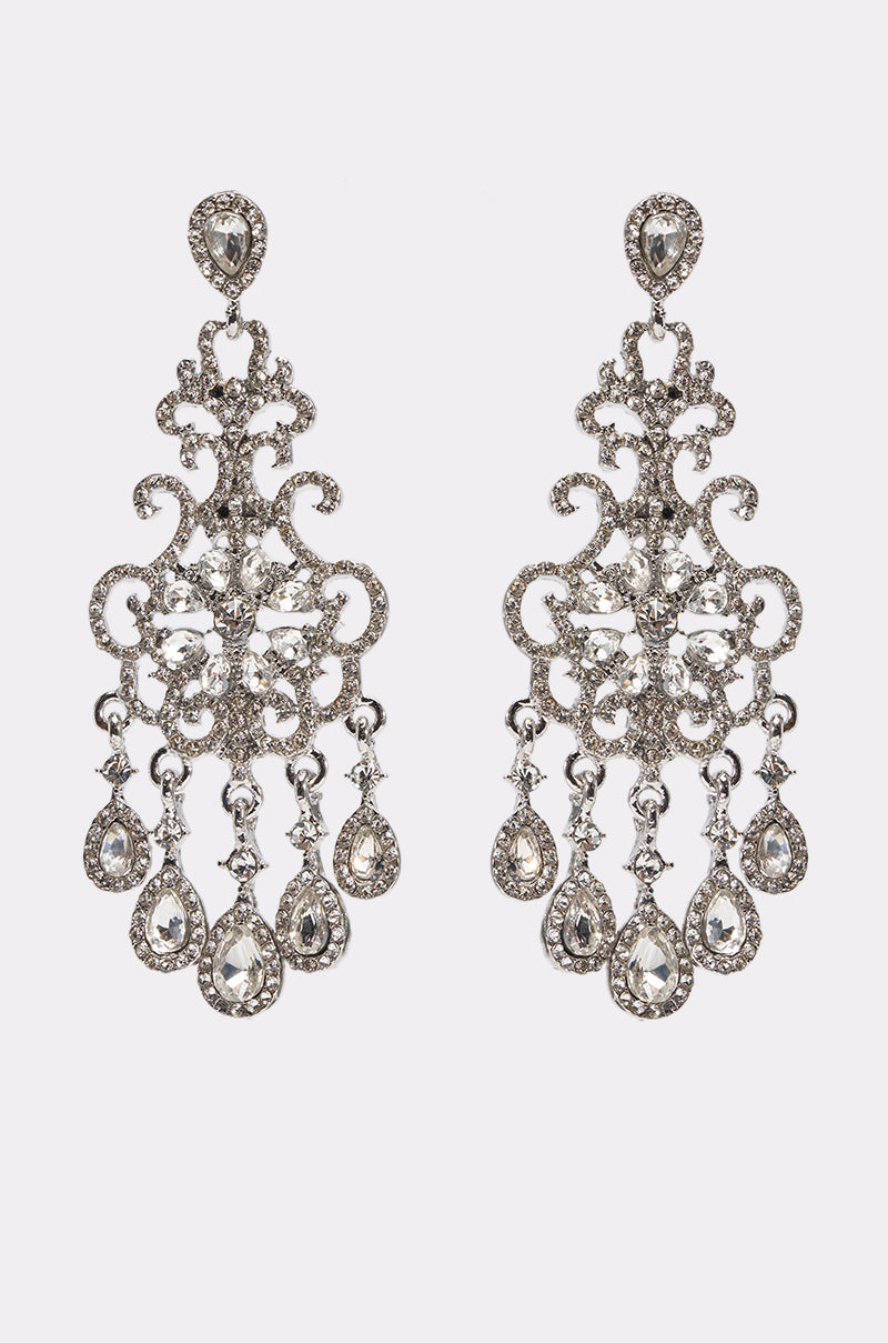 The CHANDELIER EARRING features ornate silver scrollwork and dangling teardrop rhinestones, displayed on a plain white background.