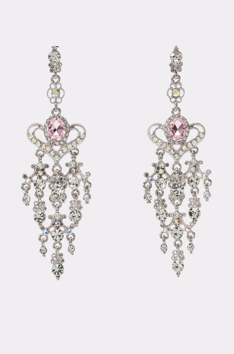 Introducing the REGAL STATEMENT EARRING: a pair of ornate silver chandelier drop earrings featuring intricate filigree, sparkling dangling crystals, and a striking large pink gemstone at the center of each, beautifully displayed against a plain white background.