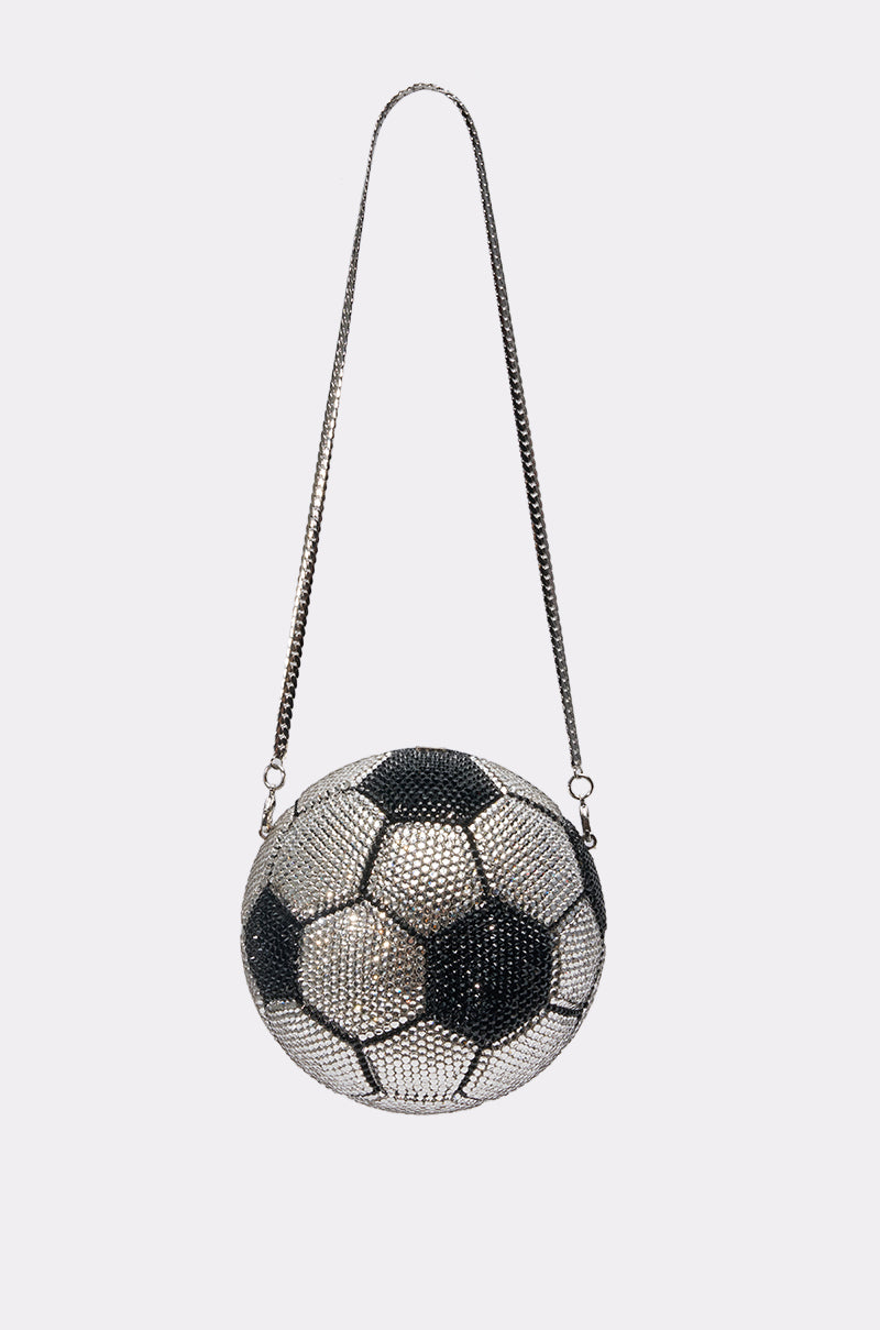 The GOAL BLING BAG is a handbag shaped like a soccer ball, adorned with black, white, and silver rhinestones, and features a long metallic chain strap, shown against a simple light background.