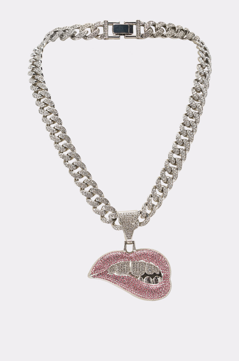 Introducing the BITE ME STATEMENT PENDANT AND CHAIN—a dazzling silver cuban-link necklace featuring a bold lip pendant encrusted with sparkling pink and clear rhinestones, playfully showcasing teeth biting the lower lip. Perfect for festival jewelry lovers seeking an eye-catching accessory.