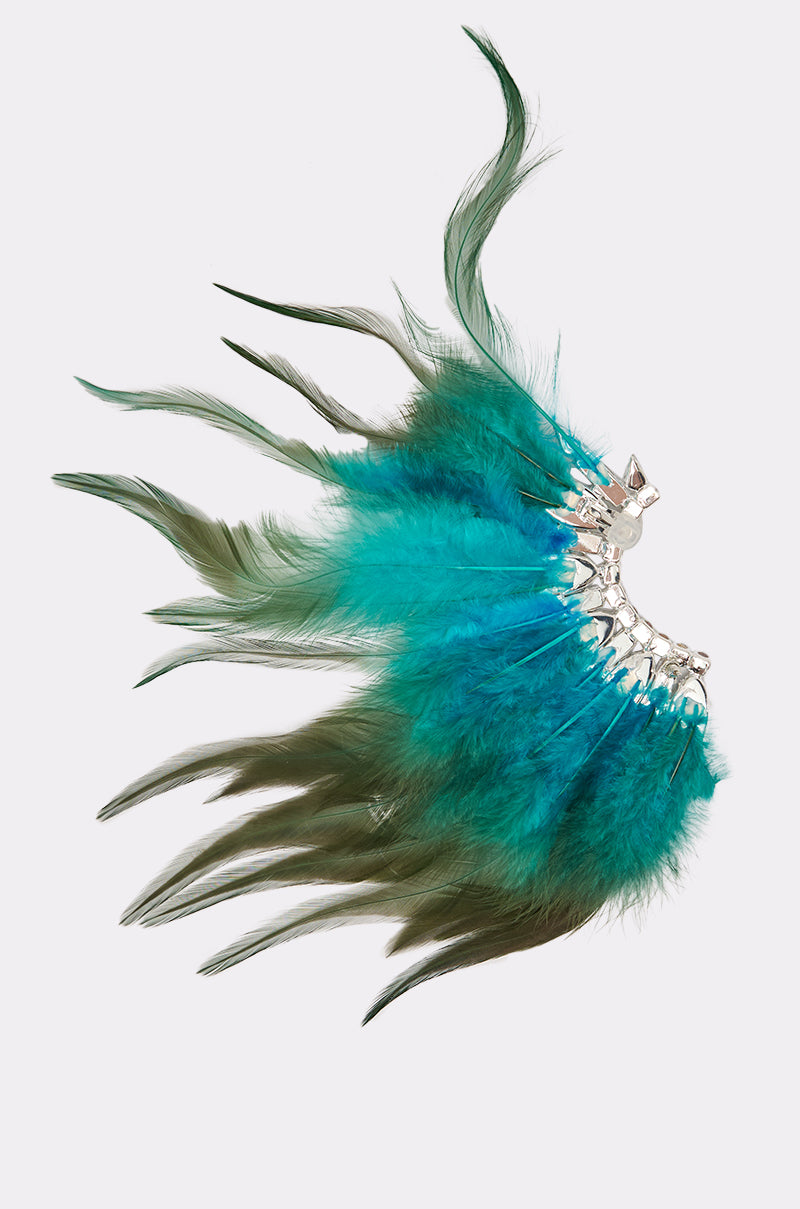 The FLY AWAY EARRING features wispy green and bright turquoise feathers fanned out from a silver metal base—a bold, decorative statement accessory. 2