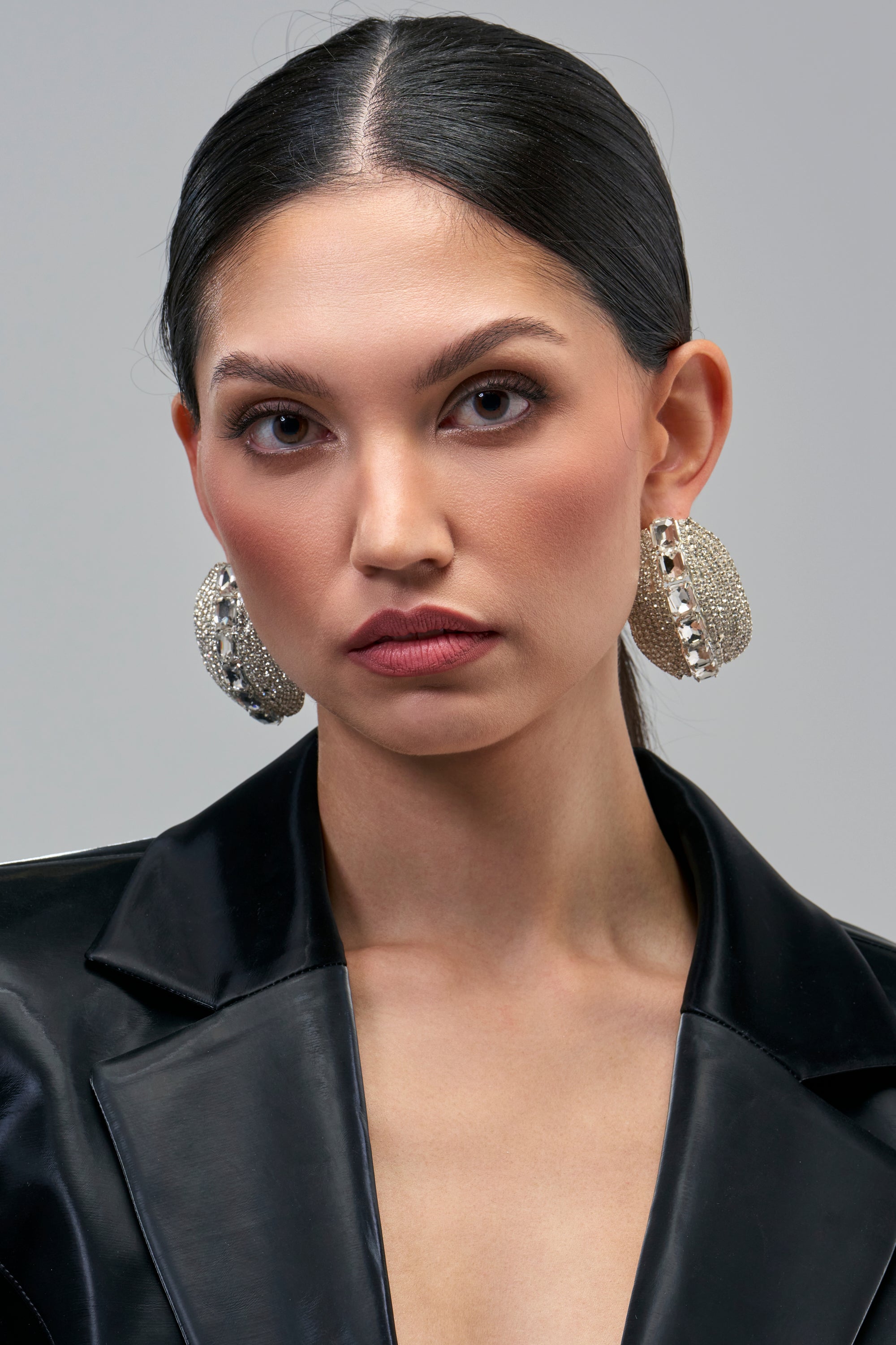 A person wearing large, circular, sparkling silver CRYSTAL CAGE STATEMENT EARRINGS.
