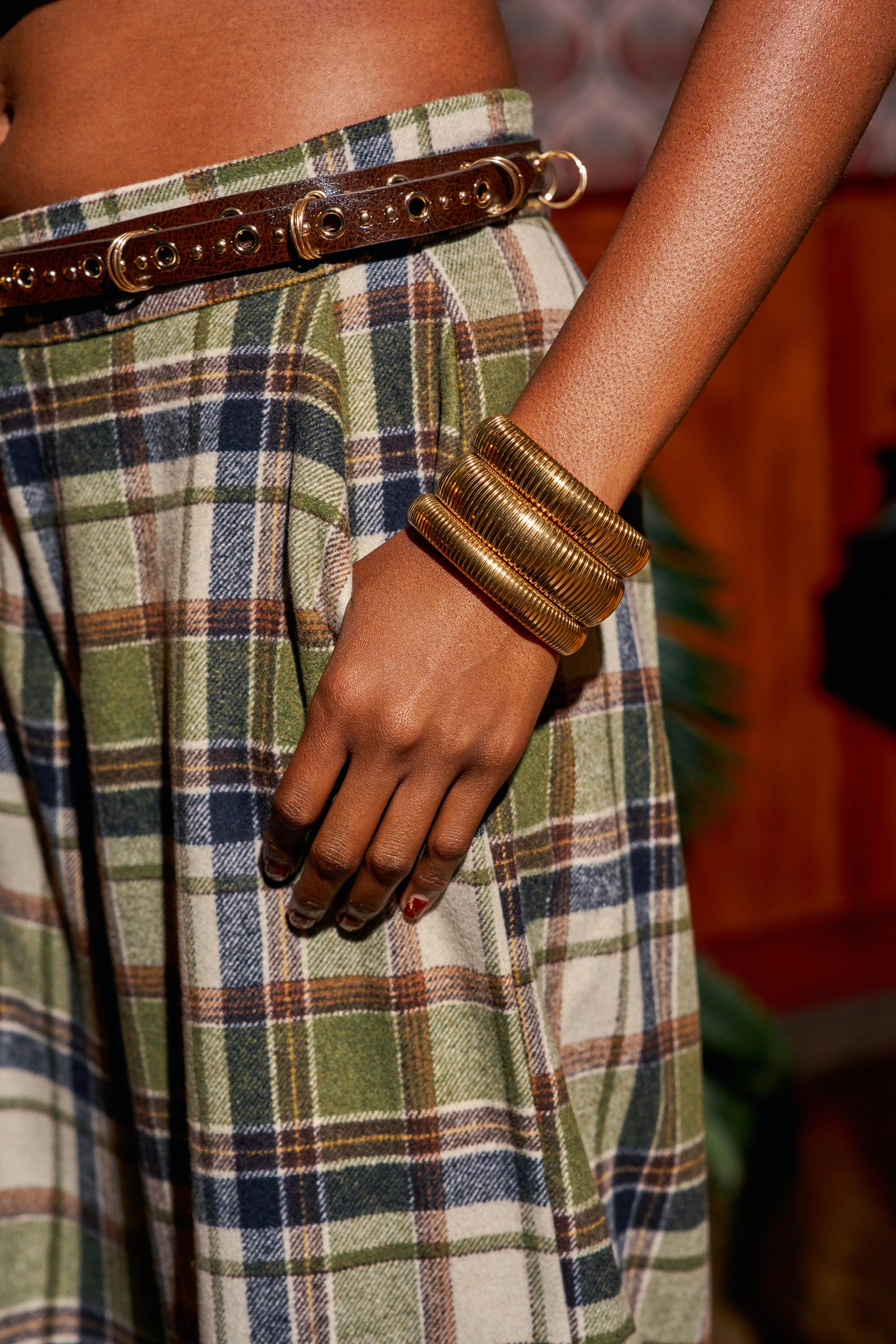 A stacked set of three gold-toned, rounded OMEGA CHAIN BRACELET SET pieces with a ribbed design worn on a wrist.