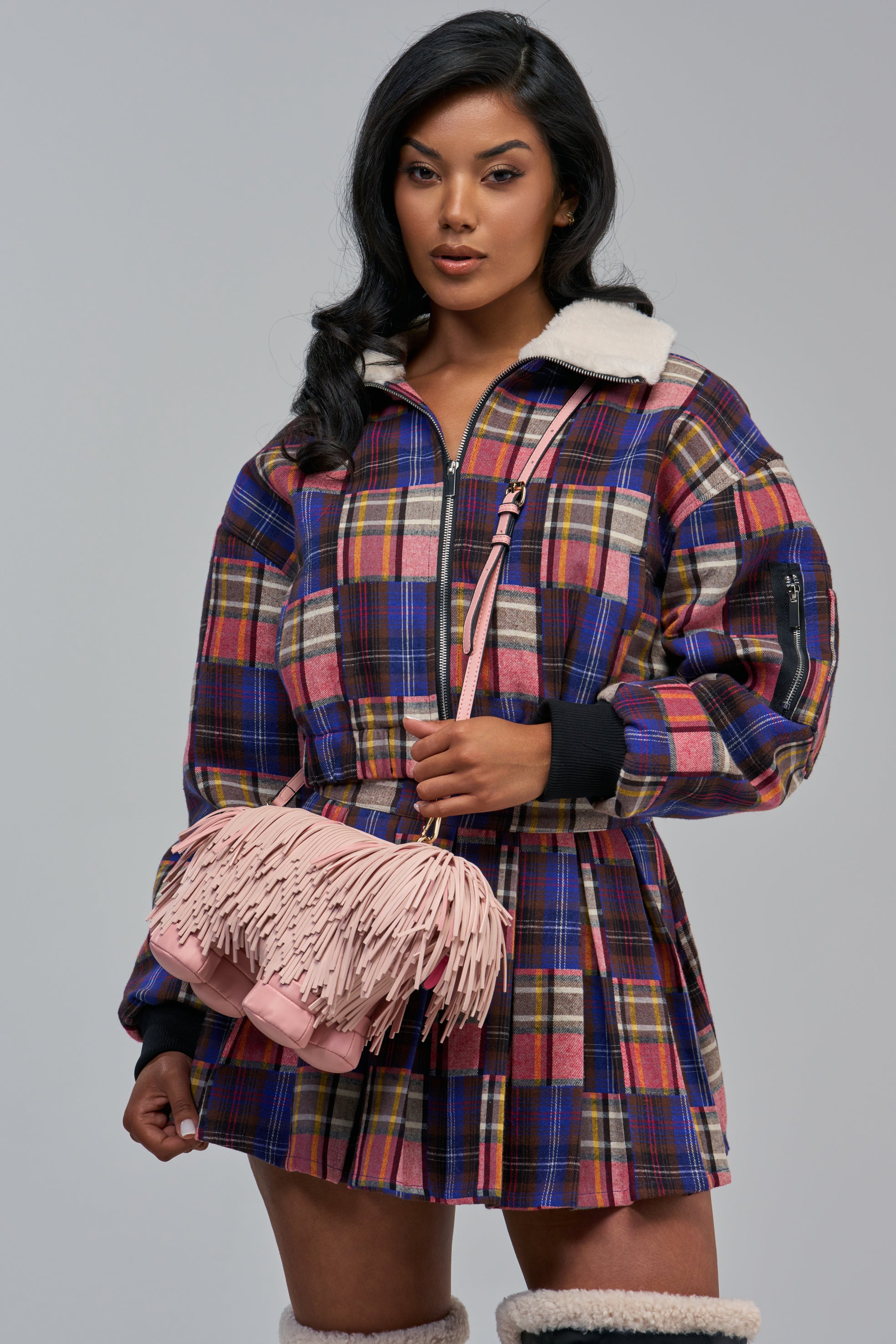 A woman wearing a plaid jacket and skirt holds a pink fringed DOGGIE IN THE WINDOW BAG shaped like a dog.