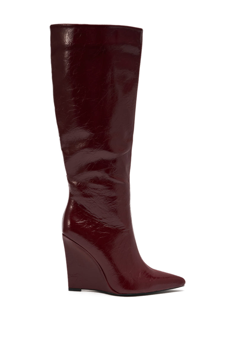 The AZALEA WANG AMAADIS BURGUNDY WEDGE KNEE HIGH BOOT is a tall, shiny knee-high boot with a wedge heel and pointed toe, shown in profile against a white background.
