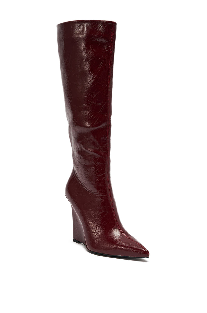 The AZALEA WANG AMAADIS BURGUNDY WEDGE KNEE HIGH BOOT, featuring a pointed toe and shiny burgundy leather, stands against a white background.
