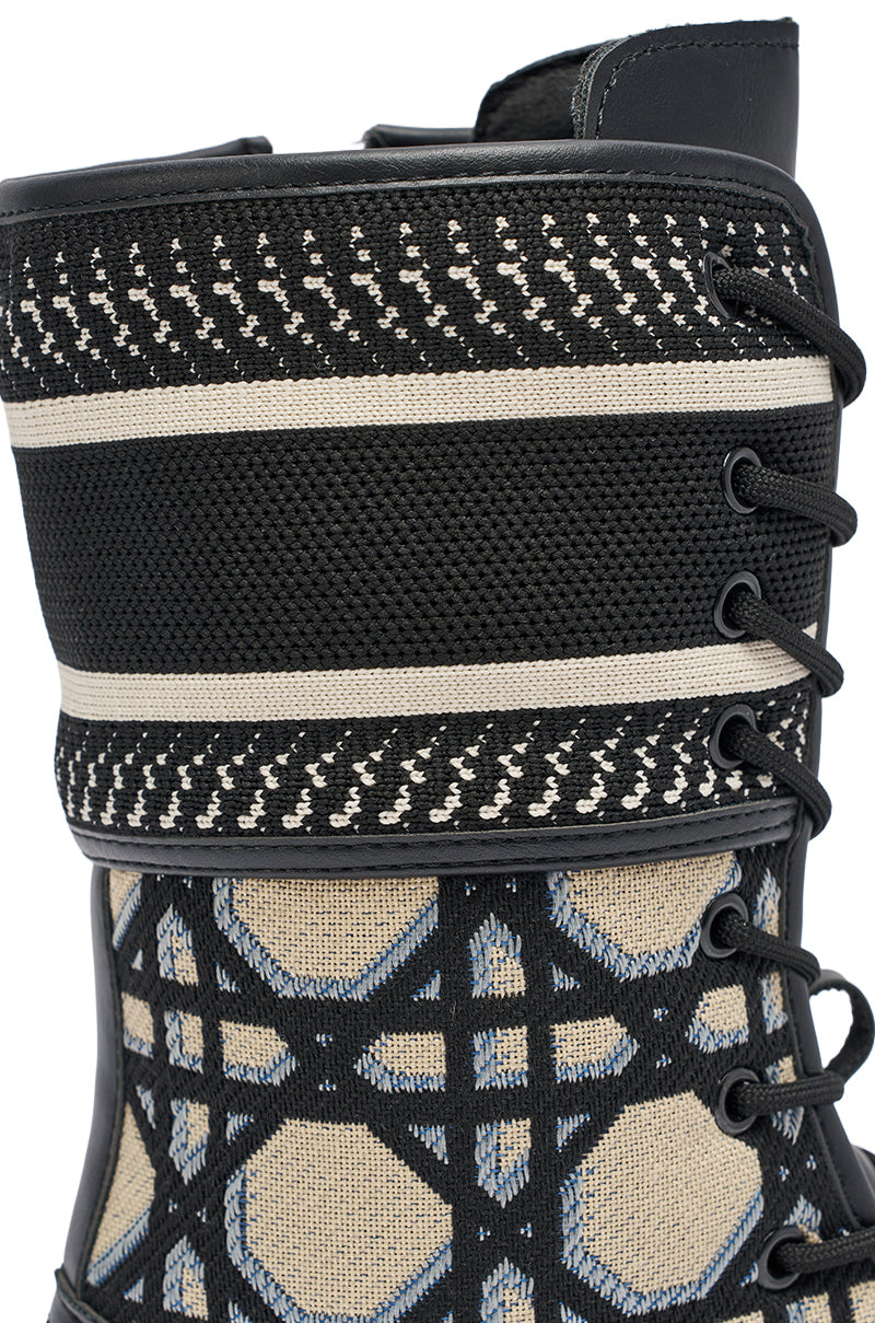 Close-up of AMADA CANVAS PRINT COMBAT BOOT, a black streetwear boot with lace-up design, beige and blue mesh accents, black laces, and textured fabric details.