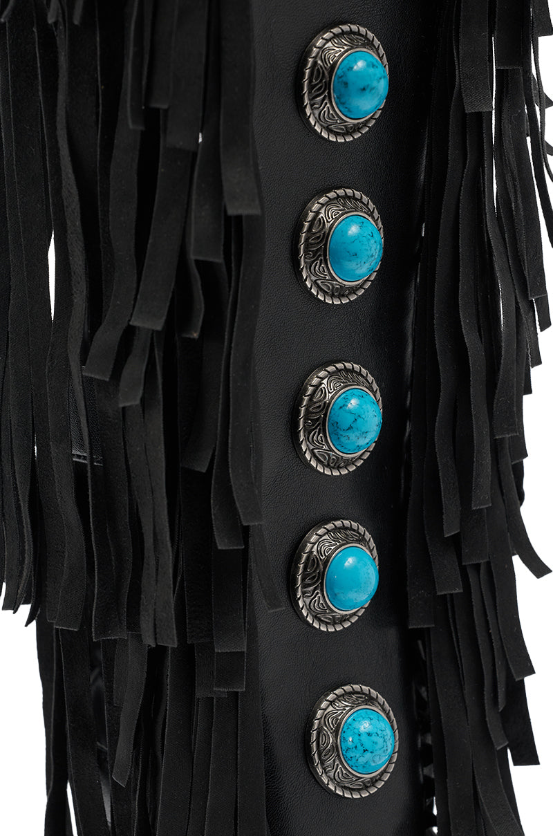 Close-up of black leather fringe on the AZALEA WANG AMADEO BLACK FRINGE AND TURQUOISE GLADIATOR STILETTO SANDAL, detailed with five ornate silver conchos featuring round turquoise stones, arranged vertically. 7
