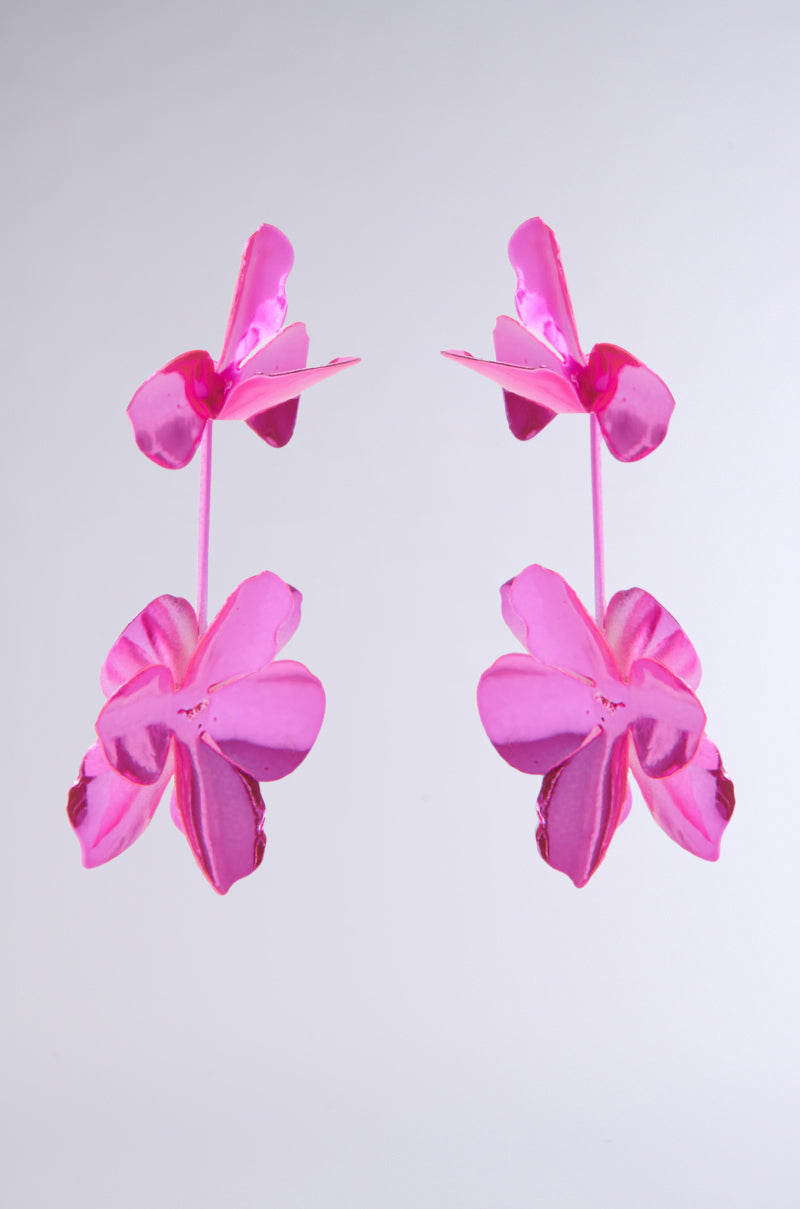 The ASH FLOWER EARRING features two mirrored hot pink flowers with five glossy, petal-like elements arranged symmetrically against a muted gray background, exuding a reflective metallic appearance. 7