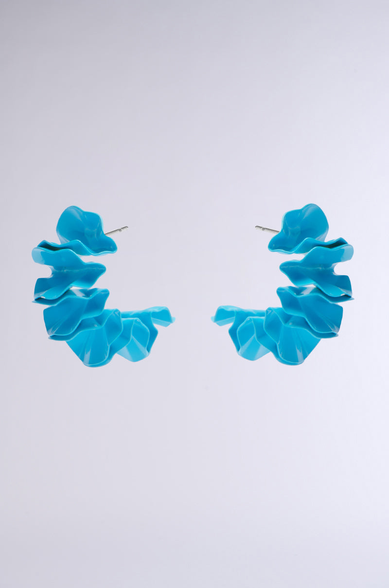 The FANNED OUT EARRING features vibrant sky blue metal shaped like abstract flower petals, artfully spiraling against a plain gray background.