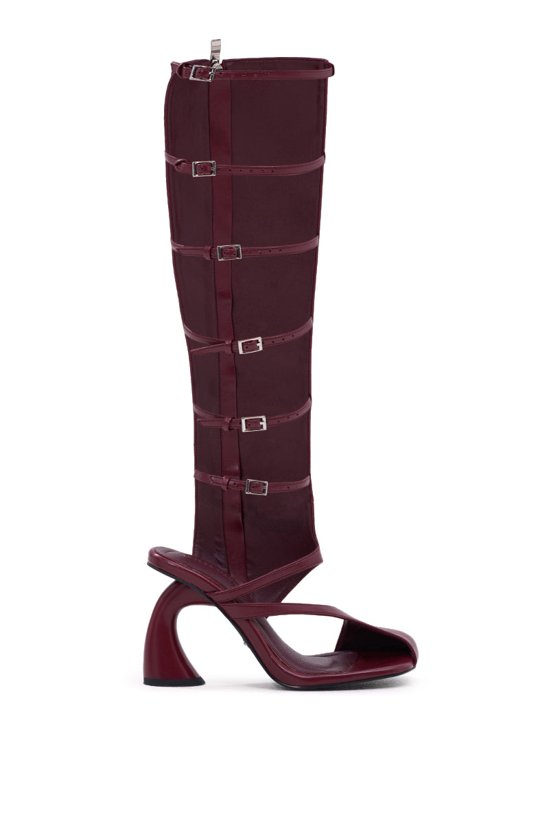 The AZALEA WANG ANDRIUS Burgundy Gladiator Sandal is a knee-high faux leather shoe with multiple horizontal straps, silver buckles, an open toe, and a sculpted chunky heel.