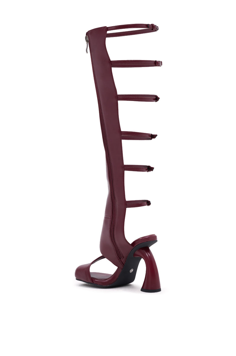 The AZALEA WANG ANDRIUS BURGUNDY GLADIATOR SANDAL is a tall faux leather style with multiple horizontal straps, an open toe, a side zipper, and a sculpted chunky heel, shown against a white background.