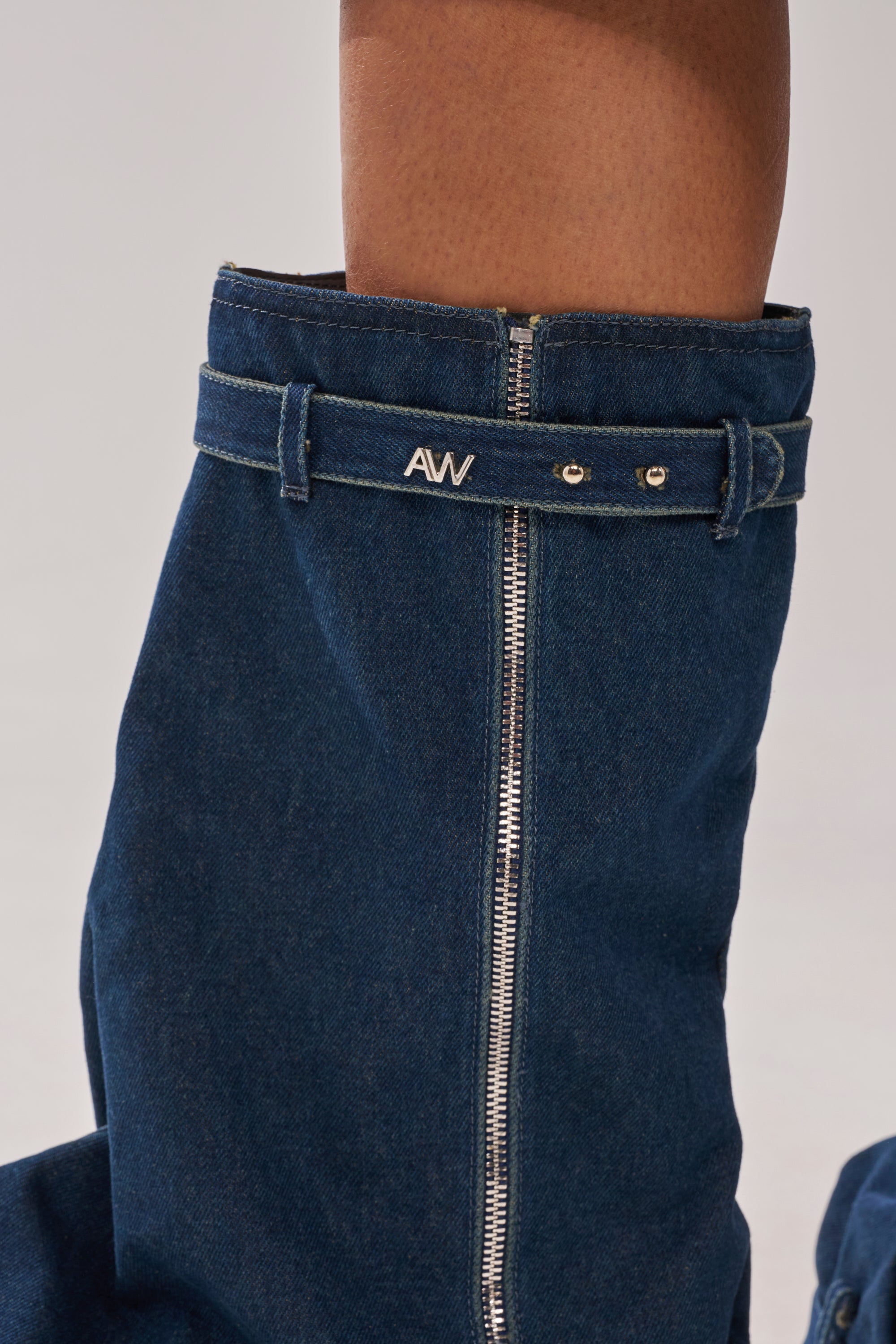 A person in high-waisted blue denim pants with a silver zipper and "AW" belt stands against a plain light background, paired with the AKIRA GOLD ANGELA FOLD OVER PLATFORM BOOT IN DARK DENIM featuring a chunky lug sole. 3