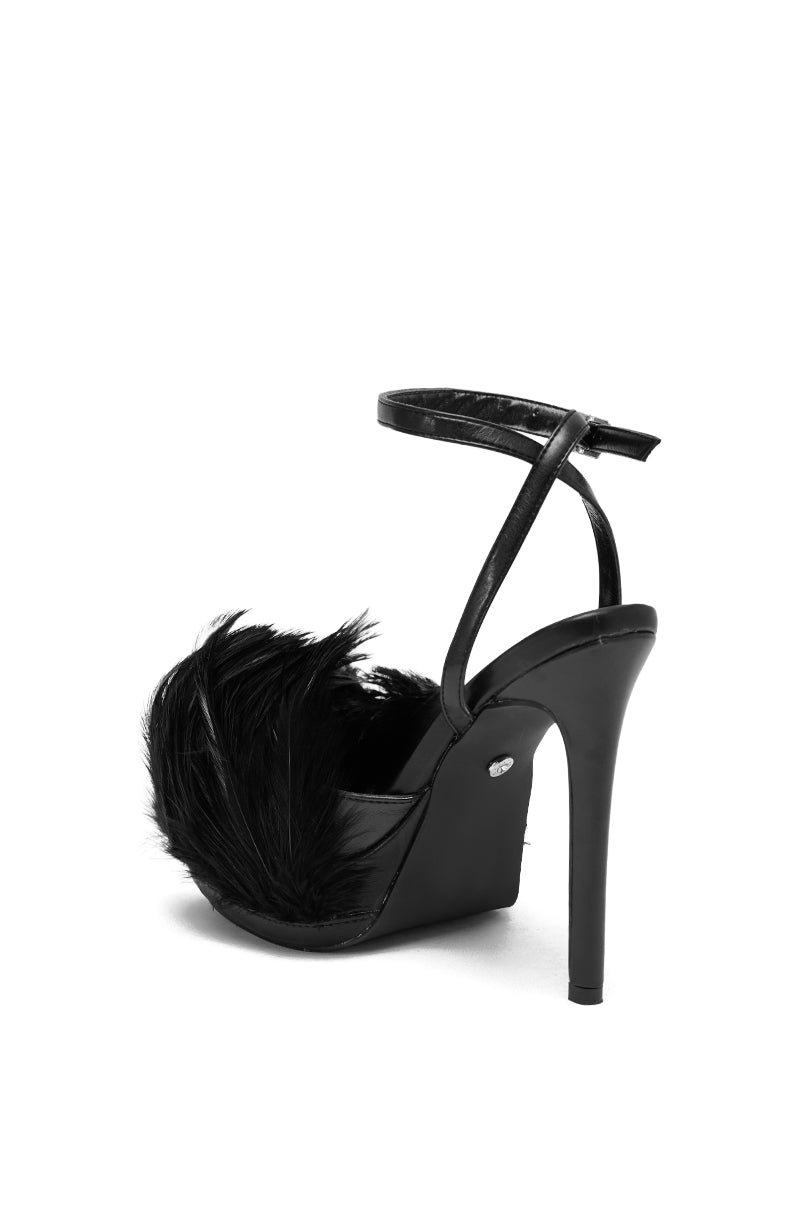 The AZALEA WANG ANGELES BLACK FEATHER STILETTO SANDAL features vegan leather, an open toe, ankle strap, and a fluffy black feather accent on the front with a sleek platform heel, displayed against a white background.