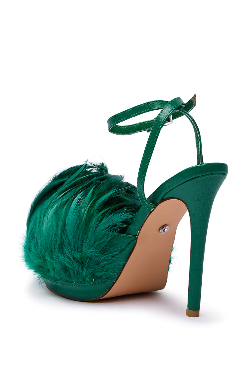 The AZALEA WANG ANGELES GREEN FEATHER STILETTO SANDAL showcases a green satin finish, tan platform sole, ankle strap, and bold feather detail on the faux leather front, displayed against a white background.