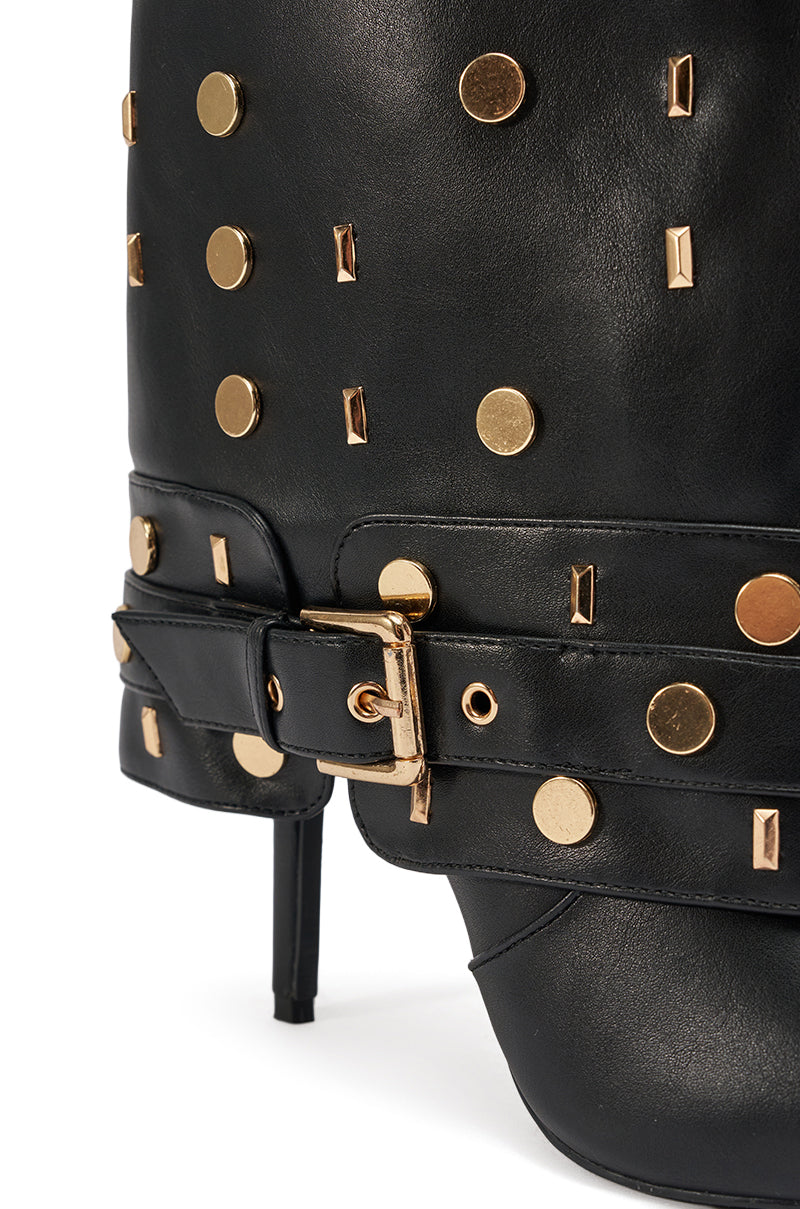 Close-up of the AZALEA WANG ANISSA BLACK MULTI GOLD HARDWARE STILETO BOOT, crafted in black faux leather with gold round and rectangular studs, a gold buckle, and a high stiletto heel.