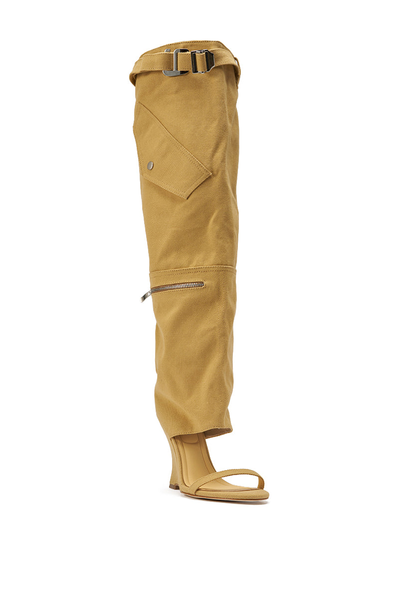 The AZALEA WANG ANOUK KHAKI SPORT WEDGE BOOT combines a tan knee-high pant leg with pockets and zippers and an open-toe wedge heel, creating a bold streetwear look that merges footwear with edgy style. 4