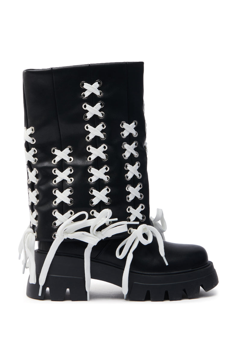 The AZALEA WANG ANSELM BLACK LACE TIE BOOTIE is a black knee-high boot in sleek faux leather, featuring chunky soles, prominent white laces crisscrossing the front and sides, bold silver eyelets, large bow knots, and a rugged yet stylish appearance with its chunky heel.