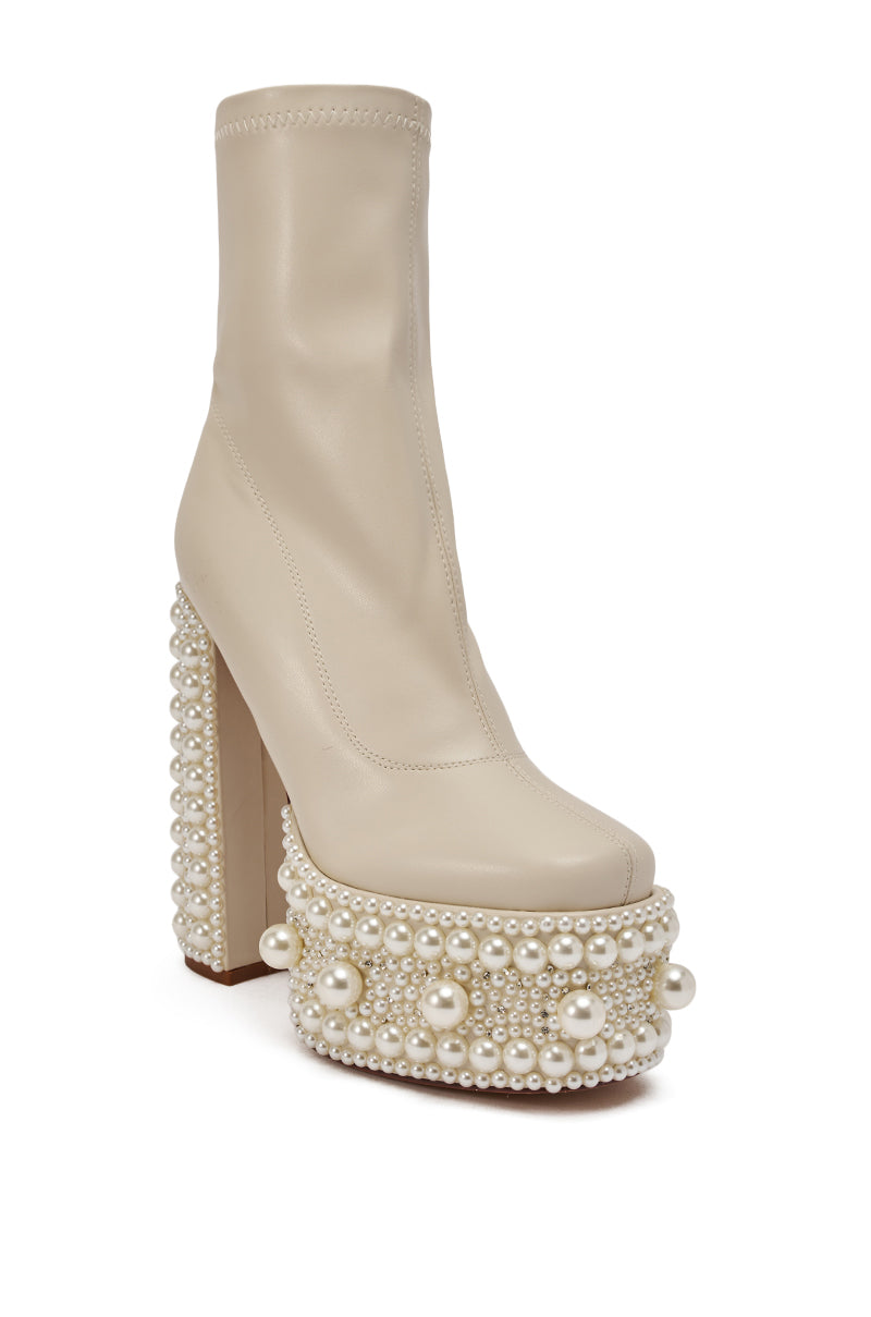 The AZALEA WANG ANTARIS Beige Pearl Detail Platform Bootie is a high-heeled faux leather bootie featuring a chunky block heel and platform sole, both adorned with decorative pearls in multiple sizes. 6