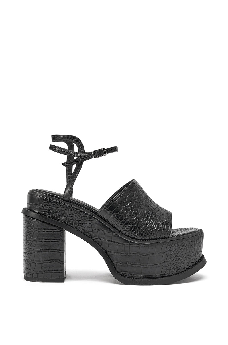 The AZALEA WANG ANTHELMINE BLACK CROC PLATFORM SANDAL features black crocodile-embossed faux leather, a chunky block heel, wide front strap, and ankle strap with buckle, displayed in side view on a white background. 3