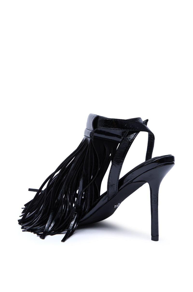 The AZALEA WANG ANTIQUE BLACK FRINGE UPPER STILETTO SANDAL features a glossy faux patent leather finish, long fringe details at the ankle, an adjustable ankle strap, open toe design, and a stiletto heel for added elegance and height.