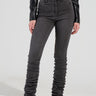 A person wearing STACKS ON STACKS high-rise skinny leg denim pants in gray and a black cropped leather jacket stands against a plain background, their feet clad in black high-heeled boots.