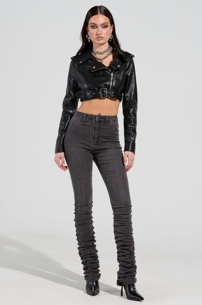 Wearing a black cropped leather jacket, layered necklaces, the STACKS ON STACKS DENIM PANT in a dark high-rise skinny leg style, and black heeled boots, the person stands confidently against a plain background. The ensemble exudes a stylish and edgy vibe. 6