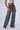 A person is posing against a plain background, showcasing the IM UP NEXT DENIM PANT in washed gray denim with horizontal stripe detailing. They are also wearing a cropped white top. Only the lower torso and legs are visible in the image.