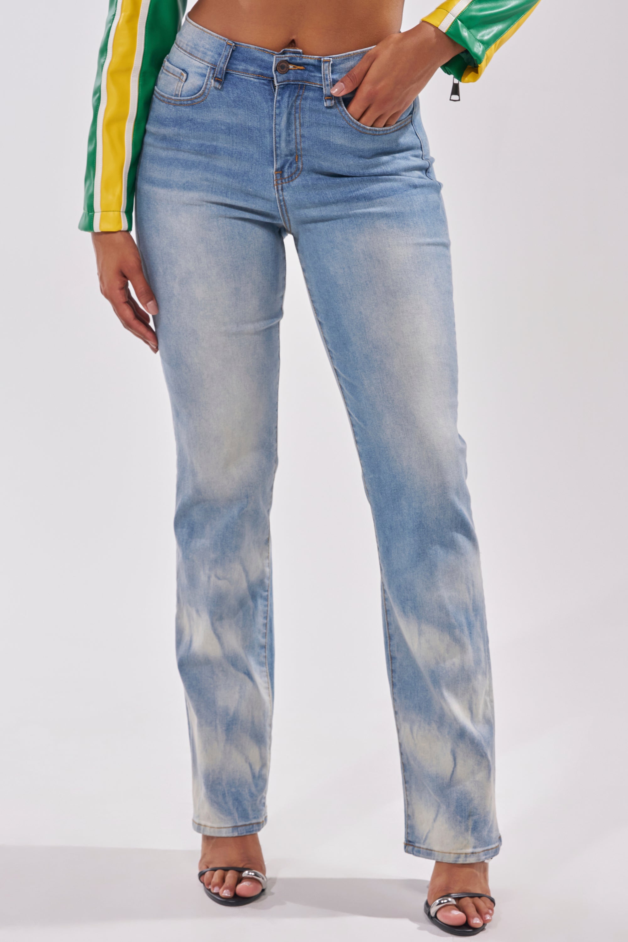 Wearing the OVER IT DENIM PANT, black heeled sandals, and a green and yellow long-sleeve jacket, a person stands with one hand in their pocket against a plain light background. 3