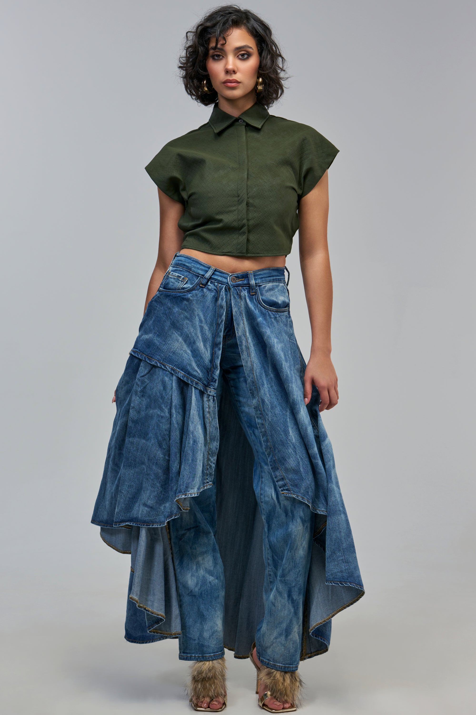 A model wears a dark green cropped button-down shirt and LOCKED UP DENIM PANT, which feature straight-leg jeans with an attached denim skirt overlay.