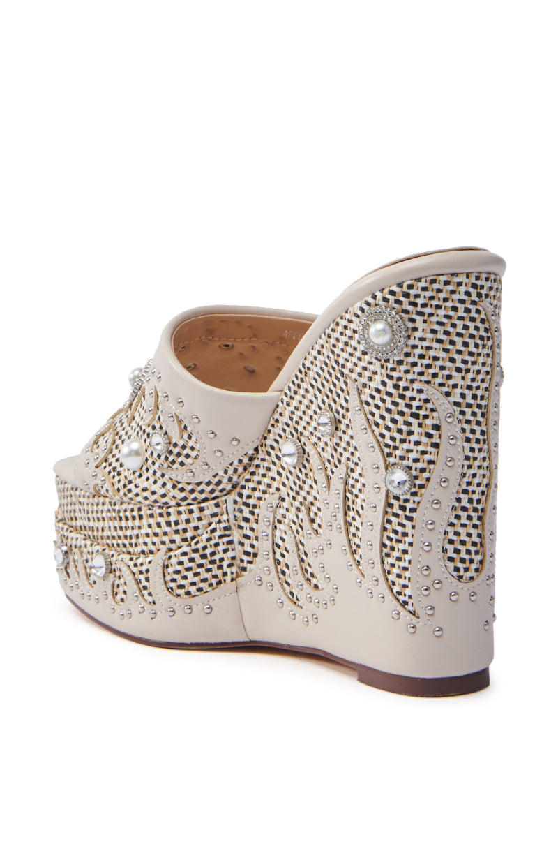 The AZALEA WANG APPOLONIA Beige Tweed Embellished Wedge Sandal features intricate designs with cream fabric, silver studs, and pearl-like embellishments. The chunky heel enhances its elegant style, while the open square toe brings a modern touch.