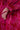 A close-up of a hand resting on the hip, wearing the AMALIA TIE NECK TRENCH—a red and pink brocade floral garment featuring a tied fabric bow on the sleeve.