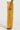 A person is seen in the lower half of a photo, modeling the DRIPPING IN GOLD CRUSHED VELVET TROUSER against a neutral backdrop. These high-rise trousers, with their mustard yellow hue, showcase a shiny and textured finish that accentuates the wide-leg silhouette.
