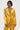 In a DRIPPING IN GOLD CRUSHED VELVET BLAZER by AKIRA Label, a person radiates elegance with a statement necklace of layered beads. Set against a plain white background, their short, styled hair perfectly complements an utterly sophisticated expression.