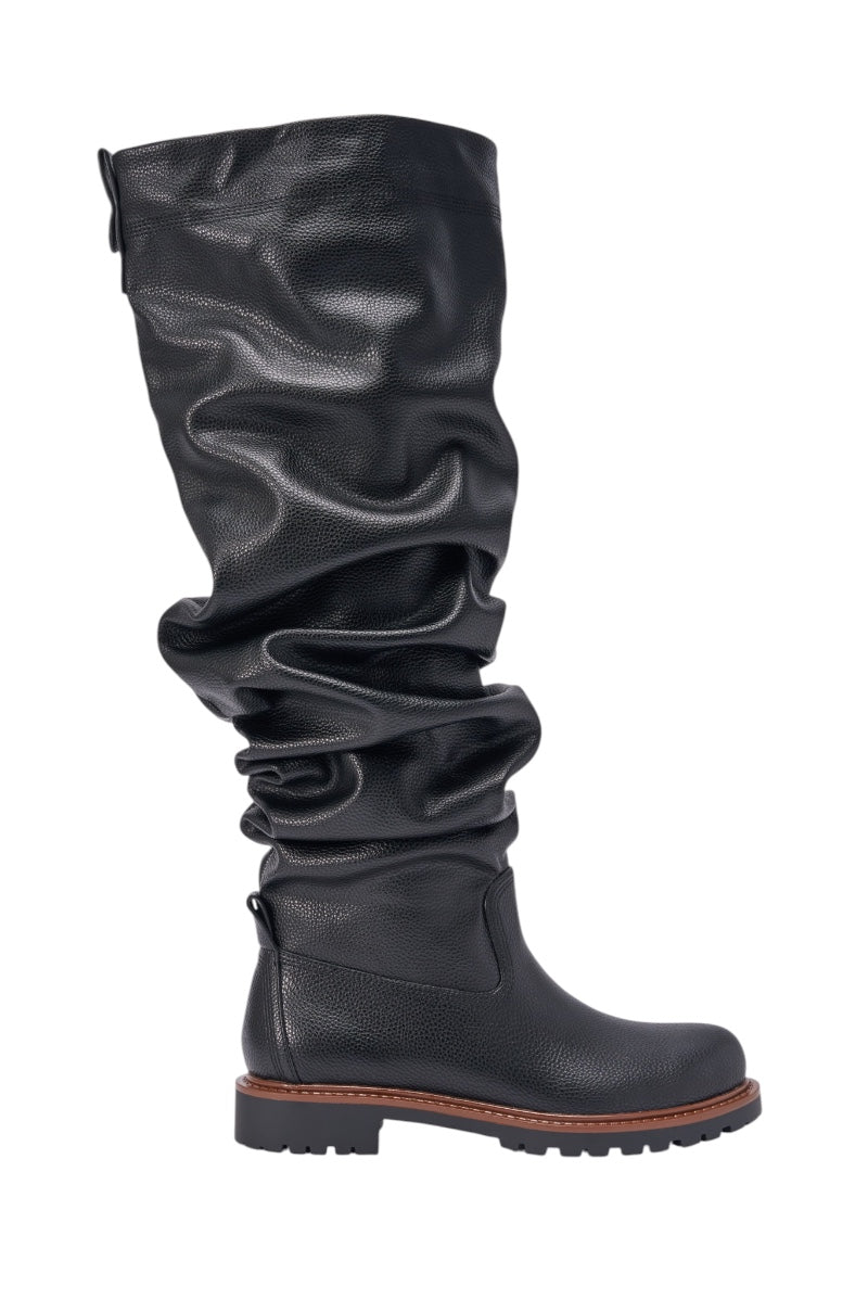 The AZALEA WANG ARDIS BLACK FLAT RUCHED BOOT features a tall black faux leather design with a round toe, textured finish, brown sole accent, and rugged tread—timeless knee-high style showcased in profile against a white background. 2