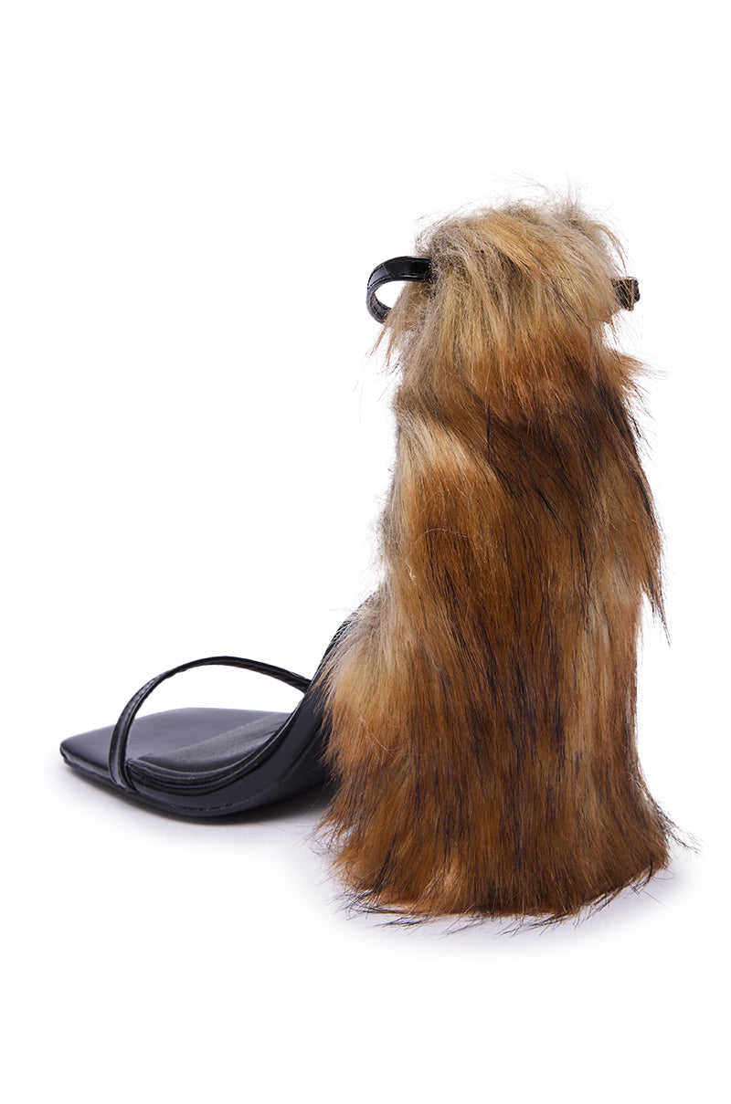 The AZALEA WANG ARETTE BLACK SANDAL WITH BROWN FUR features a chunky heel and thick brown fur, making a bold and unique fashion statement.