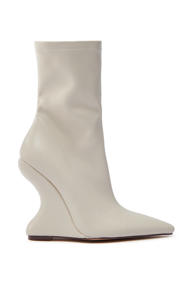 The AZALEA WANG ARKETTA bootie features a side-view of a high-heeled design with an abstract, curvy wedge heel in off-white faux leather, complemented by a sleek pointed toe and an ankle-high silhouette on a flat sole. 2